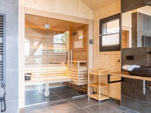 A modern bathroom with wooden accents, a glass shower enclosure, and a built-in sink. - Attractive Chalet Sauna & Hottub (Stadl-Predlitz)