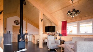 A spacious living room with a fireplace, comfortable seating, a television, and a large window with a view. - Chalet Near Ski Resort in Austria With Sauna (Stadl-Predlitz)