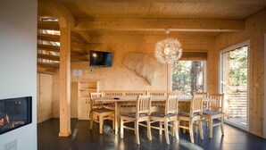 Un interno in legno con un tavolo da pranzo e sedie, un caminetto, una televisione e una grande finestra.