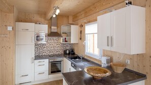 A modern kitchen with wooden walls, white cabinets, a black countertop, and a window. - Attractive Chalet With hot tub (Stadl-Predlitz)
