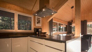 Eine moderne Küche mit Holzbalken, großen Fenstern und einer zentralen Kochinsel.
