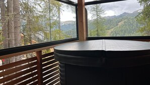 Une pièce dotée d’une grande fenêtre donnant sur un paysage de montagnes boisées.