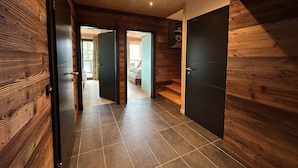 Un interior de madera con suelo de baldosas, una cama y una puerta que da a otra habitación.
