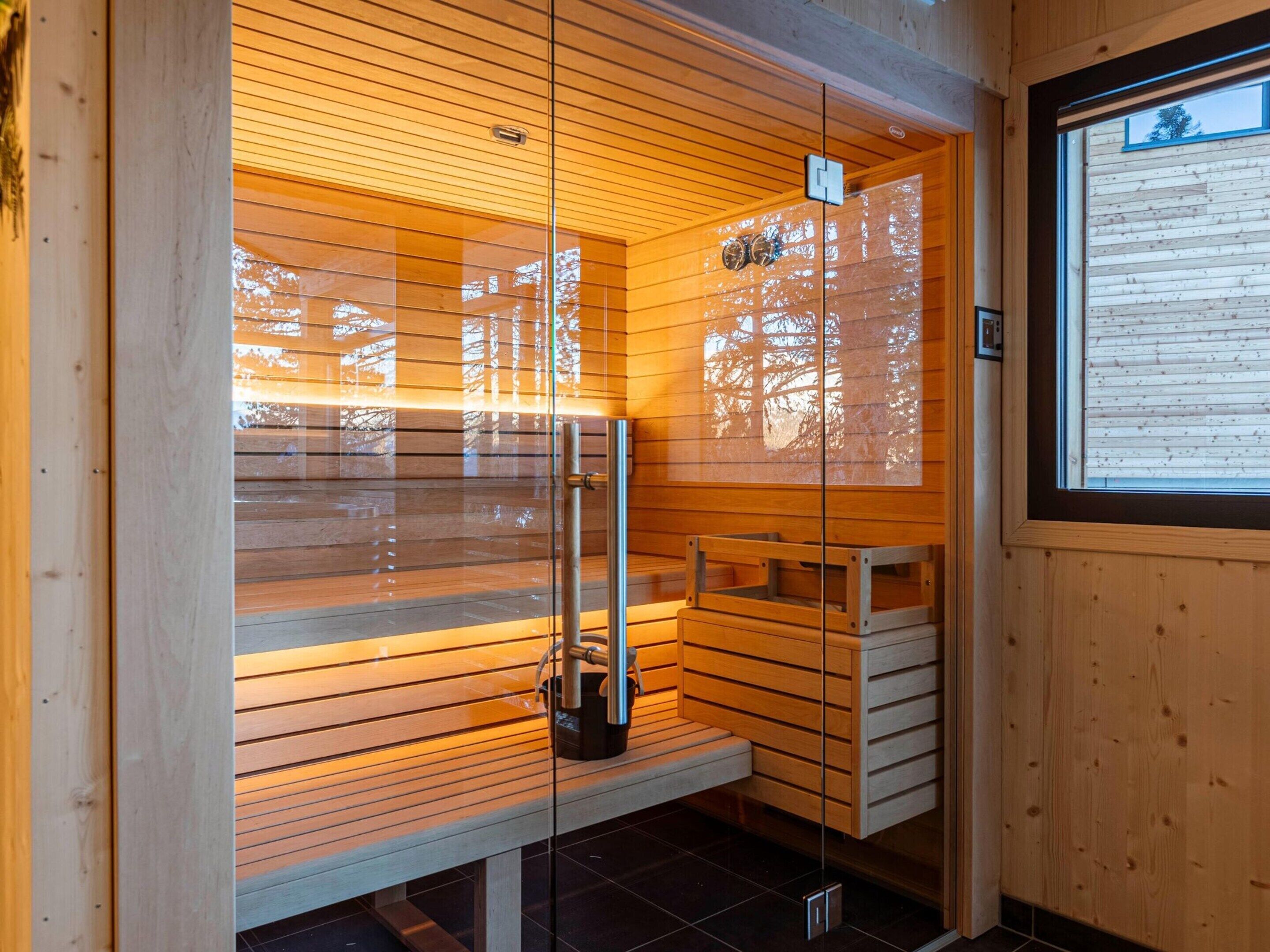 A sauna with wooden slats, a bench, and a glass door.