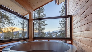Un baño moderno con una bañera independiente, ventanas amplias y paredes de madera.