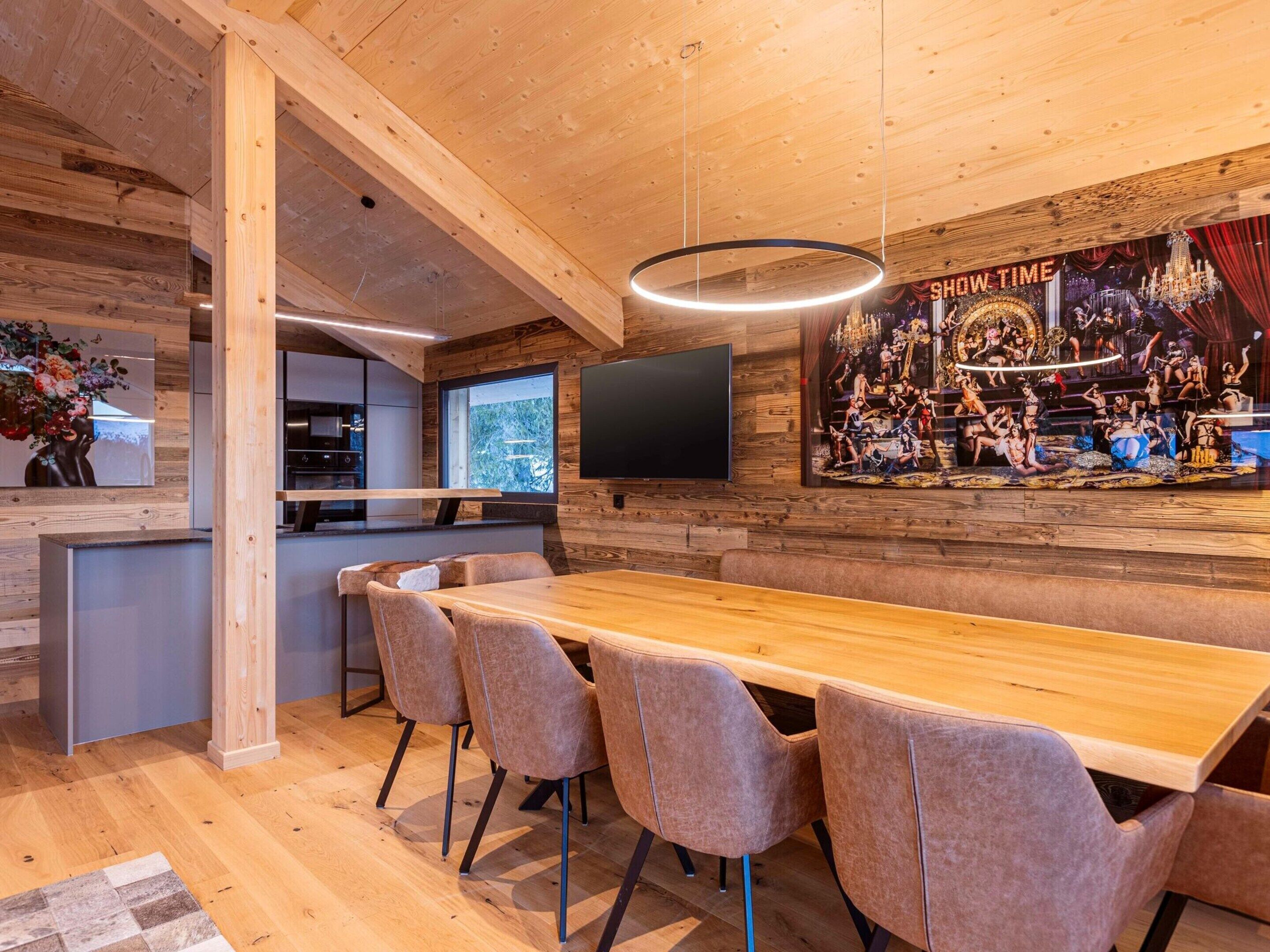 Una cocina moderna con armarios de madera, una isla grande y un comedor con una mesa larga y sillas.