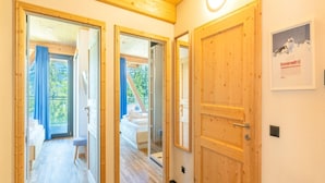 Un couloir avec des portes en bois donnant sur une chambre et un balcon.