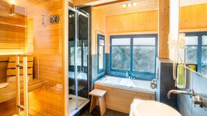 L’intérieur d’un chalet en bois comprend un sauna, une douche en verre, une baignoire et une grande fenêtre.