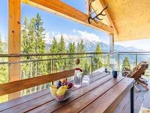 A wooden deck with a table, a bowl of fruit, and a bottle of water. - Superior Chalet With Sauna (Schladming)