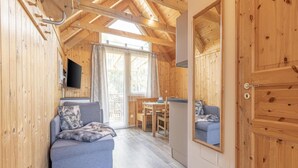 A cozy cabin interior with a wooden ceiling, a sofa, a dining table, and a television mounted on the wall. - Attractive Studio With Balcony (Sankt Georgen am Kreischberg)