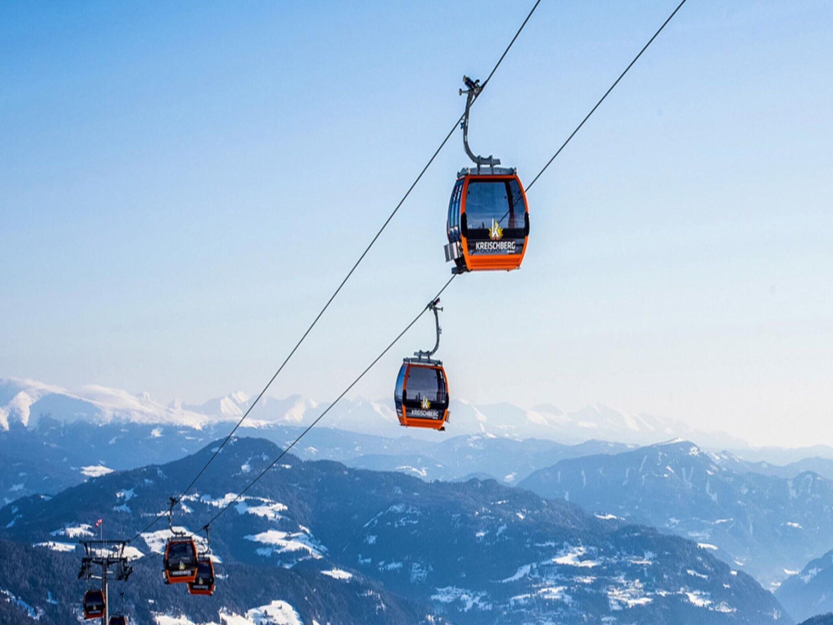A cable car system with multiple gondolas suspended by cables against a mountainous backdrop.