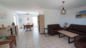 A modern living room with a sofa, coffee table, and dining area with chairs. - Eco Retreat by the Sea (Breskens)