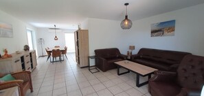 A modern living room with a sofa, coffee table, and dining area with chairs. - Eco Retreat by the Sea (Breskens)