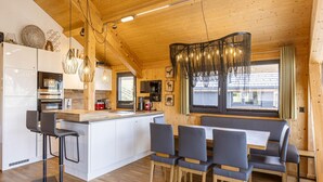 A modern kitchen with white cabinets, a central island, and bar stools. - Appealing Chalet With Sauna (Schladming)