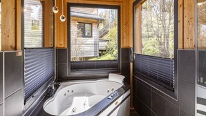 A modern bathroom with a freestanding bathtub, large windows, and wooden paneling. - Appealing Chalet With Sauna (Schladming)
