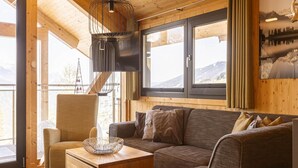 A cozy cabin interior with a wooden ceiling, a sofa, a chair, and a table with a woven basket. - Appealing Chalet With Sauna (Schladming)