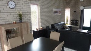 Eine moderne Küche mit Backsteinwand, einem Esstisch mit Stühlen, einer schwarzen Couch und einem Kamin.