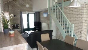 Ein modernes Wohnzimmer mit Essbereich, Treppe und Fernseher.