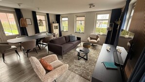 Uma sala de estar moderna com sofá, poltronas, mesa de jantar e aparador para TV.
