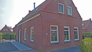 Uma casa de tijolos vermelhos com telhado empena e chaminé, com a placa numérica '40'.