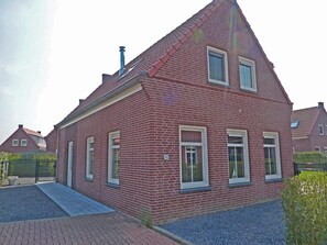 Ein rotes Backsteinhaus mit Giebeldach, Schornstein und der Hausnummer 40.