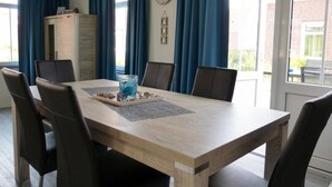 Zona pranzo con tavolo in legno, sei sedie, orologio e tende blu.