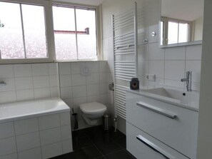 Bathroom features a white bathtub, toilet, and sink with single faucets, plus a large window and towel rack.