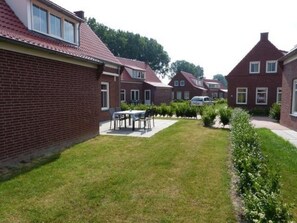 Residential homes with pitched roofs and dormer windows line the streets, surrounded by a well-manicured lawn and neatly trimmed hedges.