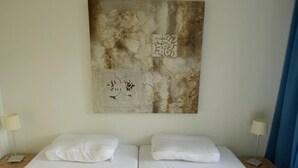 A hotel room with two beds, a large abstract painting on the wall, and two bedside lamps. - Holiday Home in Breskens Near the Beach (Breskens)