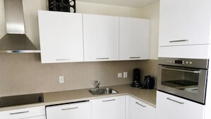 A modern kitchen with white cabinets, stainless steel appliances, and a built-in oven. - Holiday Home in Breskens Near the Beach (Breskens)