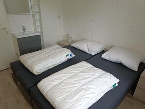 A double bed with white bedding, a bedside table with a lamp, and a small shelf unit. - House in Breskens Near Beach and Lighthouse (Breskens)