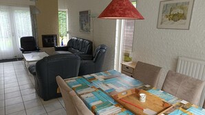 A living room with a sofa, a coffee table, a red lamp, and a painting on the wall. - House in Breskens Near Beach and Lighthouse (Breskens)