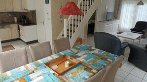 A dining area with a wooden table, chairs, a red pendant light, and a staircase leading to another level. - House in Breskens Near Beach and Lighthouse (Breskens)