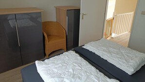 A bedroom with a bed, a wardrobe, a chair, and a door leading to a balcony. - House in Breskens Near Beach and Lighthouse (Breskens)