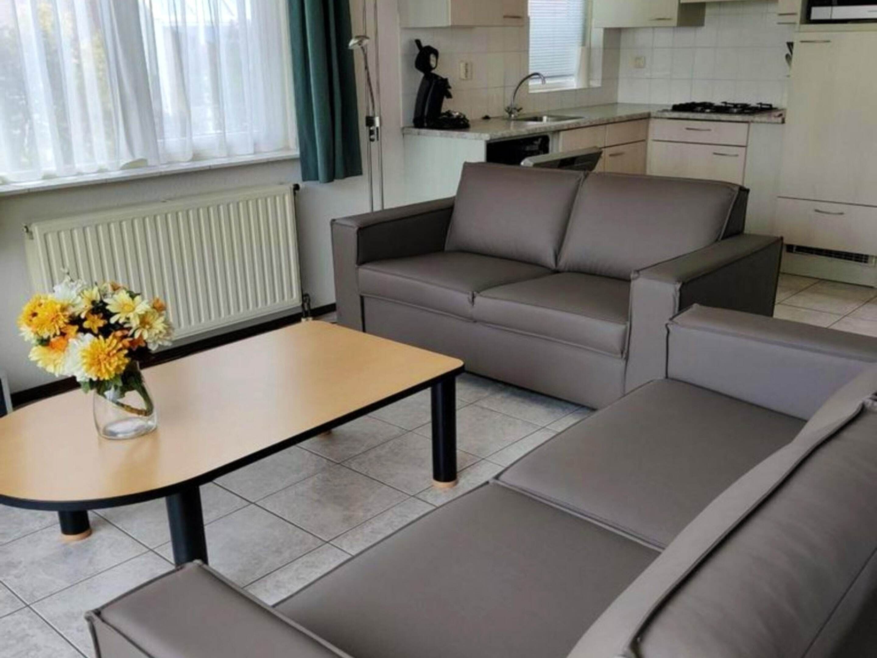 A modern living room with a sofa, a coffee table, and a vase of flowers.