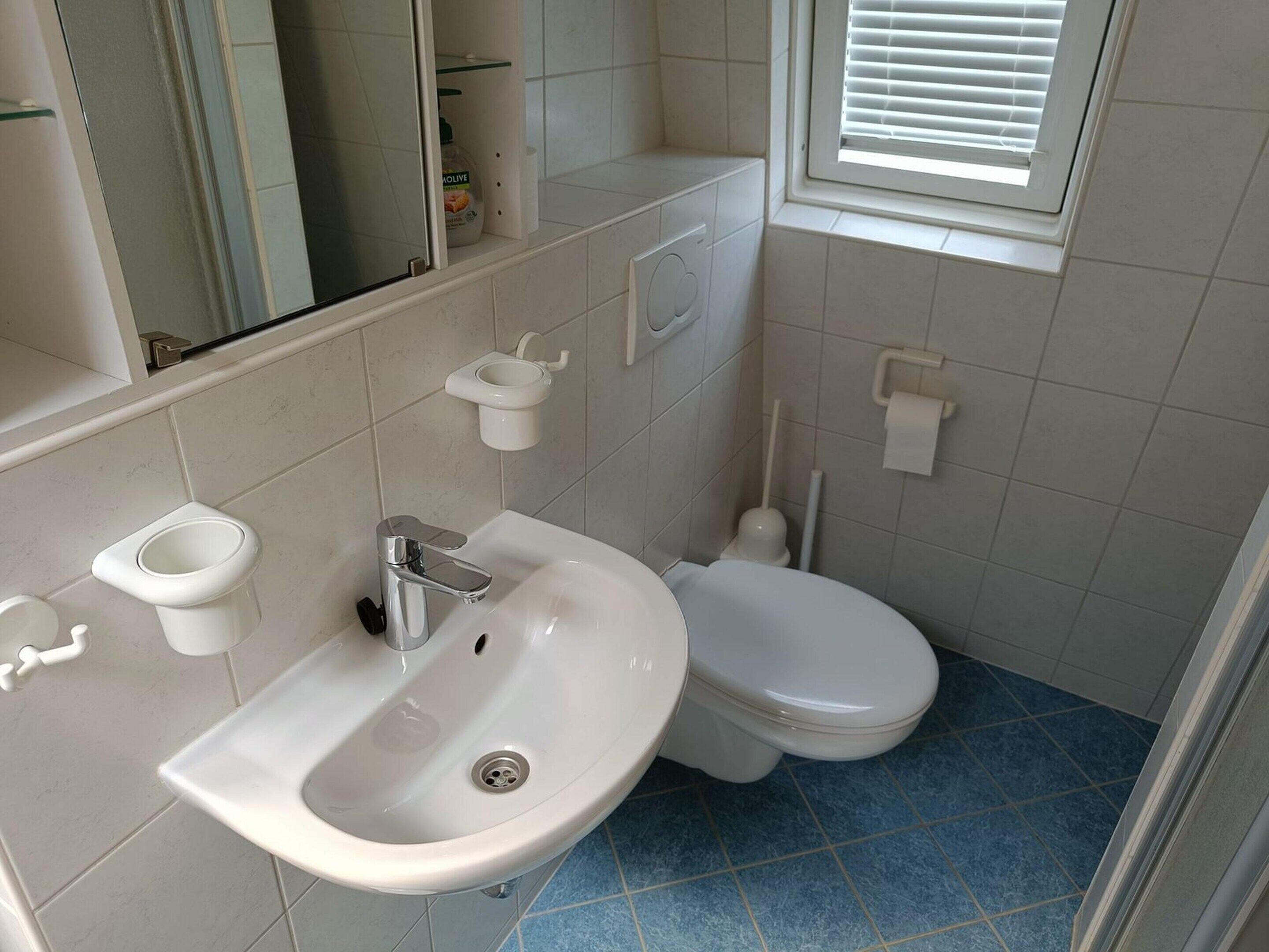 Een badkamer met een wastafel, toilet en raam.