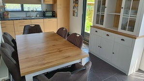 Eine kleine Küche mit Holztisch, Stühlen, Schränken und einem Fenster.