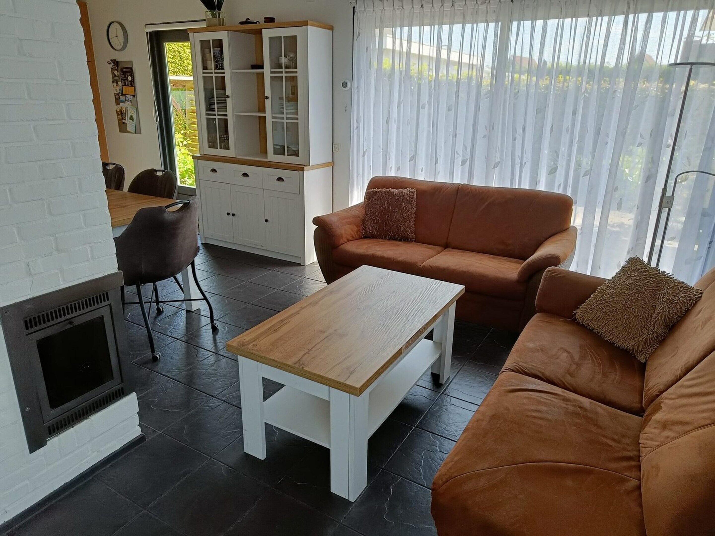 A living room with a fireplace, a sofa, a coffee table, and a kitchen area with cabinets.