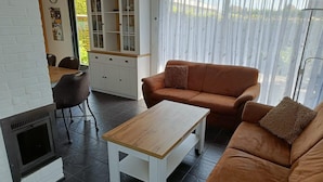 Ein Wohnzimmer mit Kamin, einer Couch, einem Couchtisch und einer Küchenzeile mit Schränken.