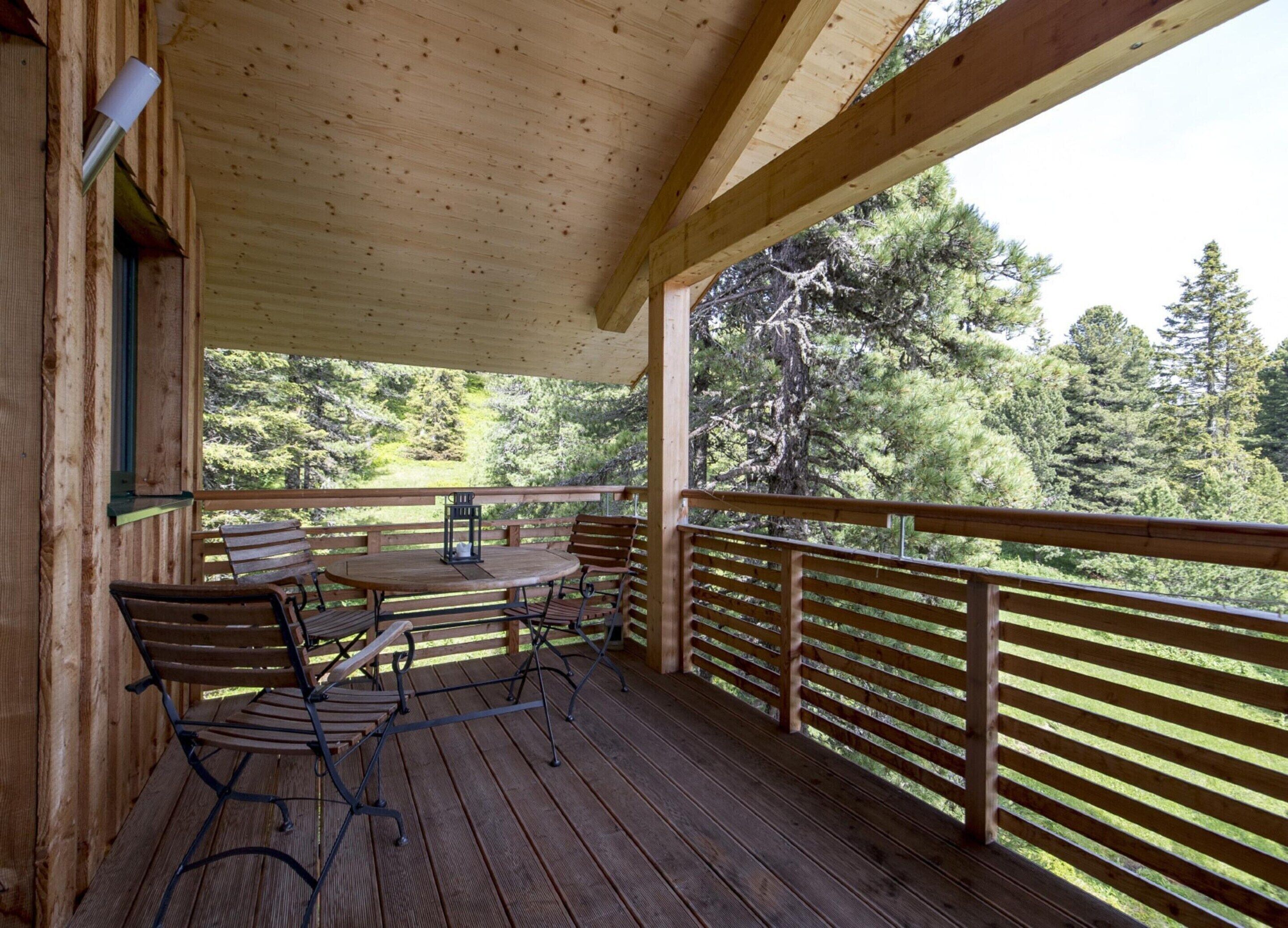 Une terrasse en bois avec une table et des chaises, donnant sur une zone boisée.