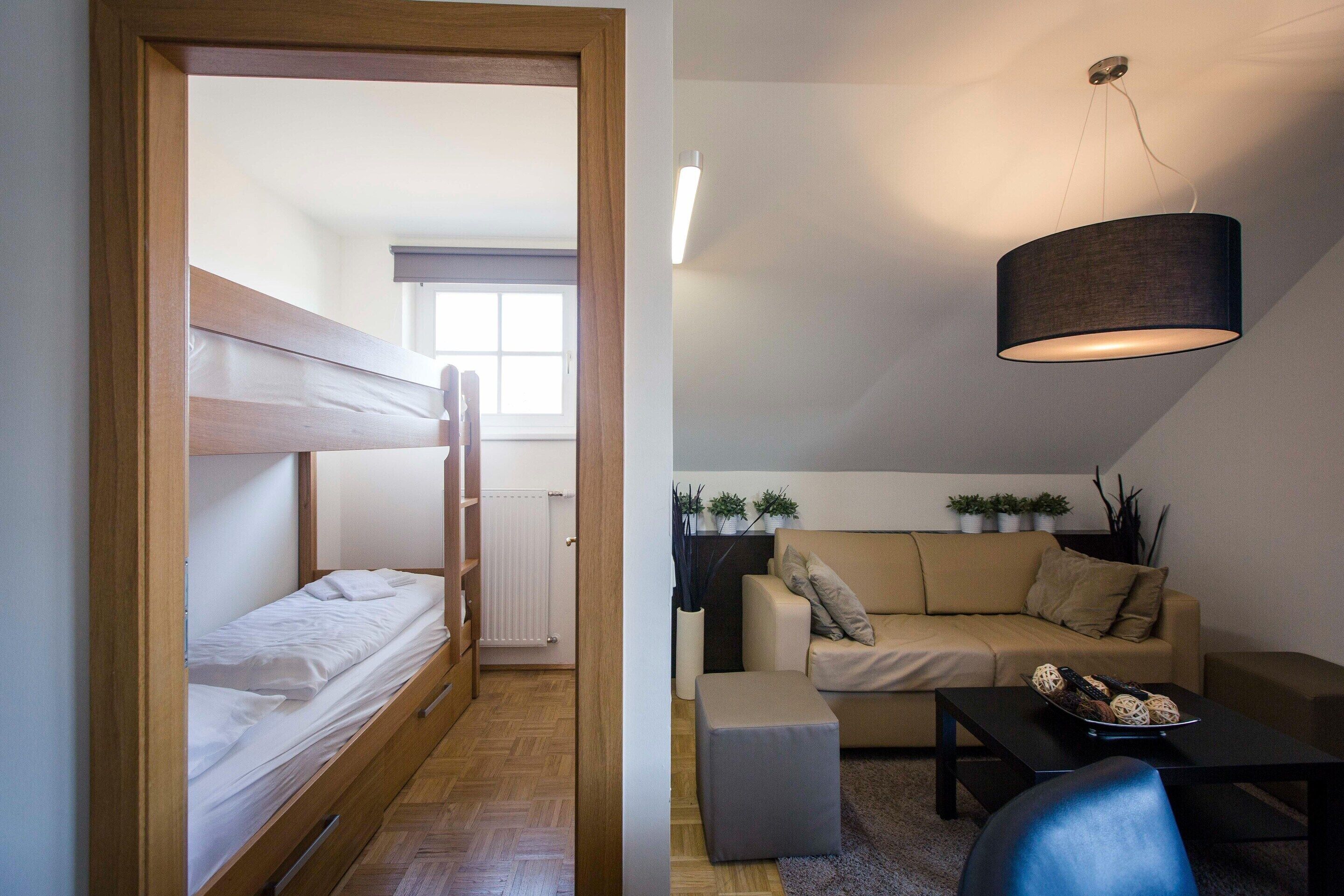 A compact room with a bunk bed, a sofa, a coffee table, and a hanging lamp.