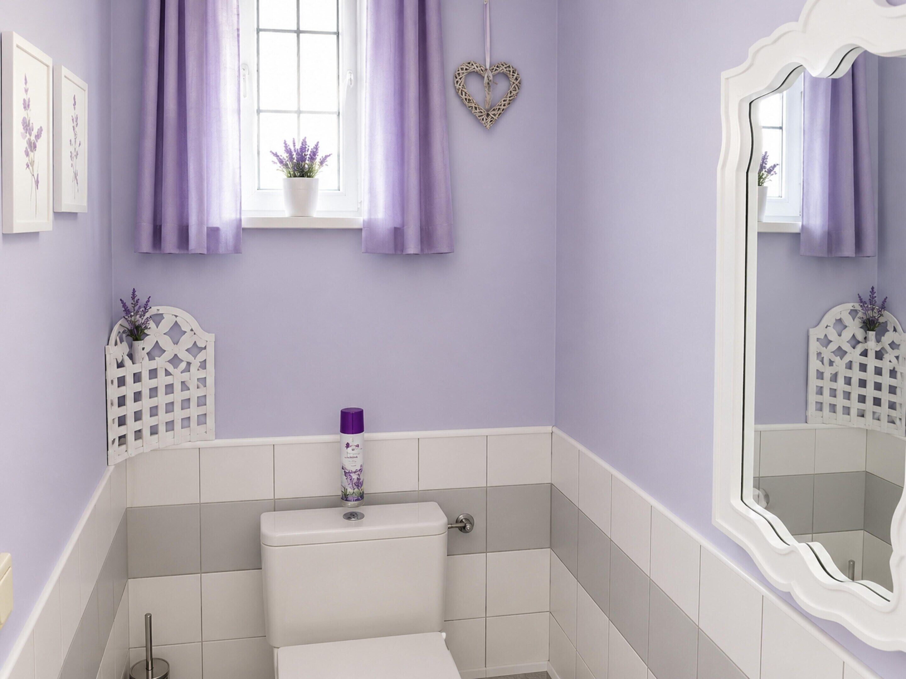 A bathroom with a toilet, a sink, a mirror, and a window with purple curtains.