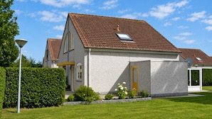 A two-story house with a red-tiled roof, a visible chimney, and a well-maintained lawn. - Bungalow in Breskens Near the Beach (Breskens)