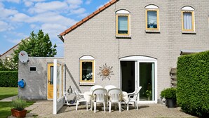 A two-story building with a brick exterior, a yellow door, and a sun decoration on the wall. - Bungalow in Breskens Near the Beach (Breskens)