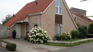 A two-story house with a red-tiled roof, a brick facade, and a front porch. - Bungalow in Breskens Near the Lighthouse (Breskens)