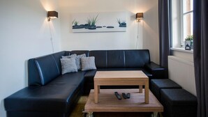 A modern living room with a black leather sofa, a wooden coffee table, and two wall-mounted lamps. - Studio Apartment in Alps Near Ski Station (Stadl-Predlitz)
