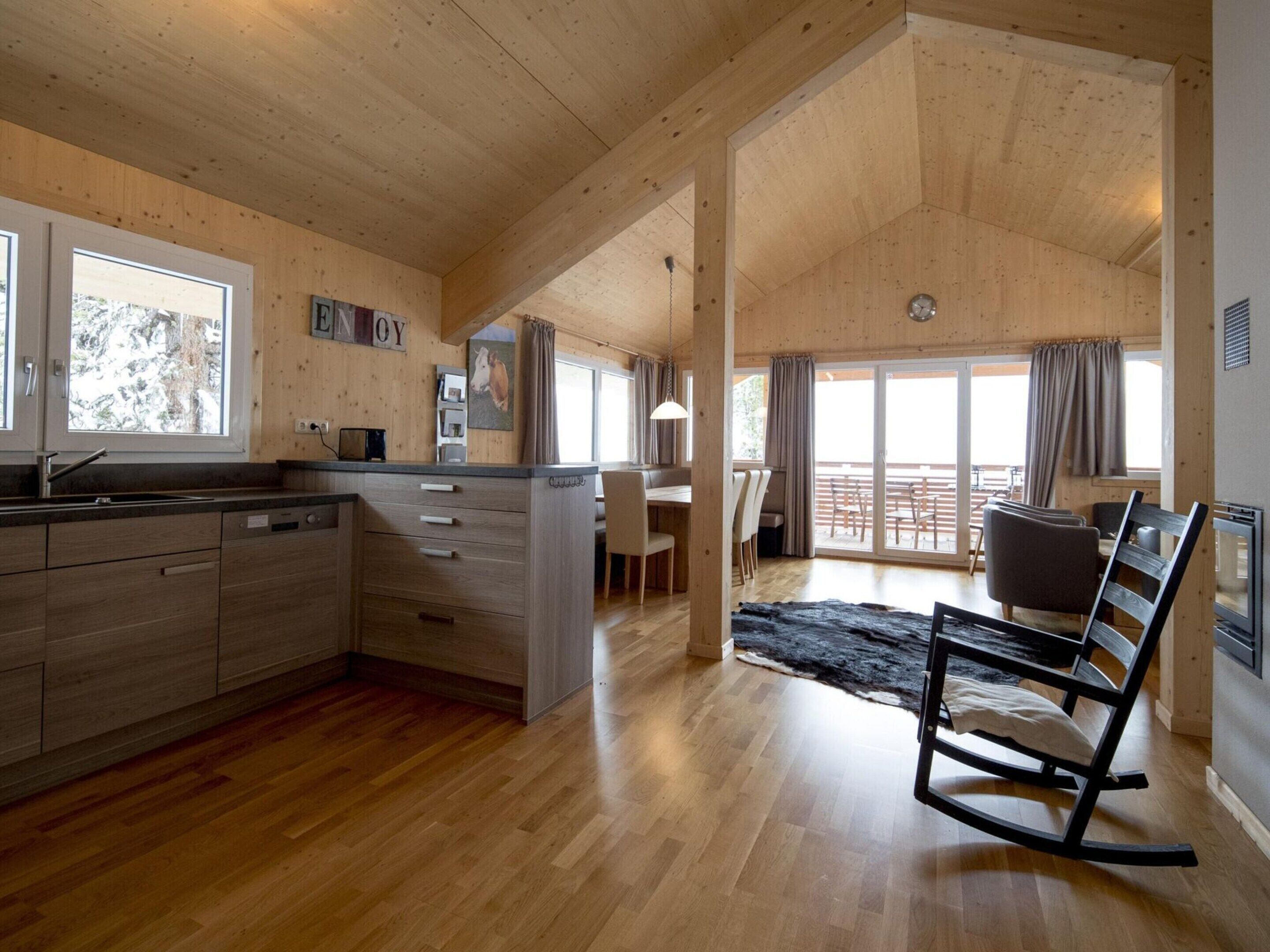 Ein geräumiges Wohnzimmer mit Holzböden, eine Küche mit Kochinsel und ein Essbereich mit Blick ins Freie.