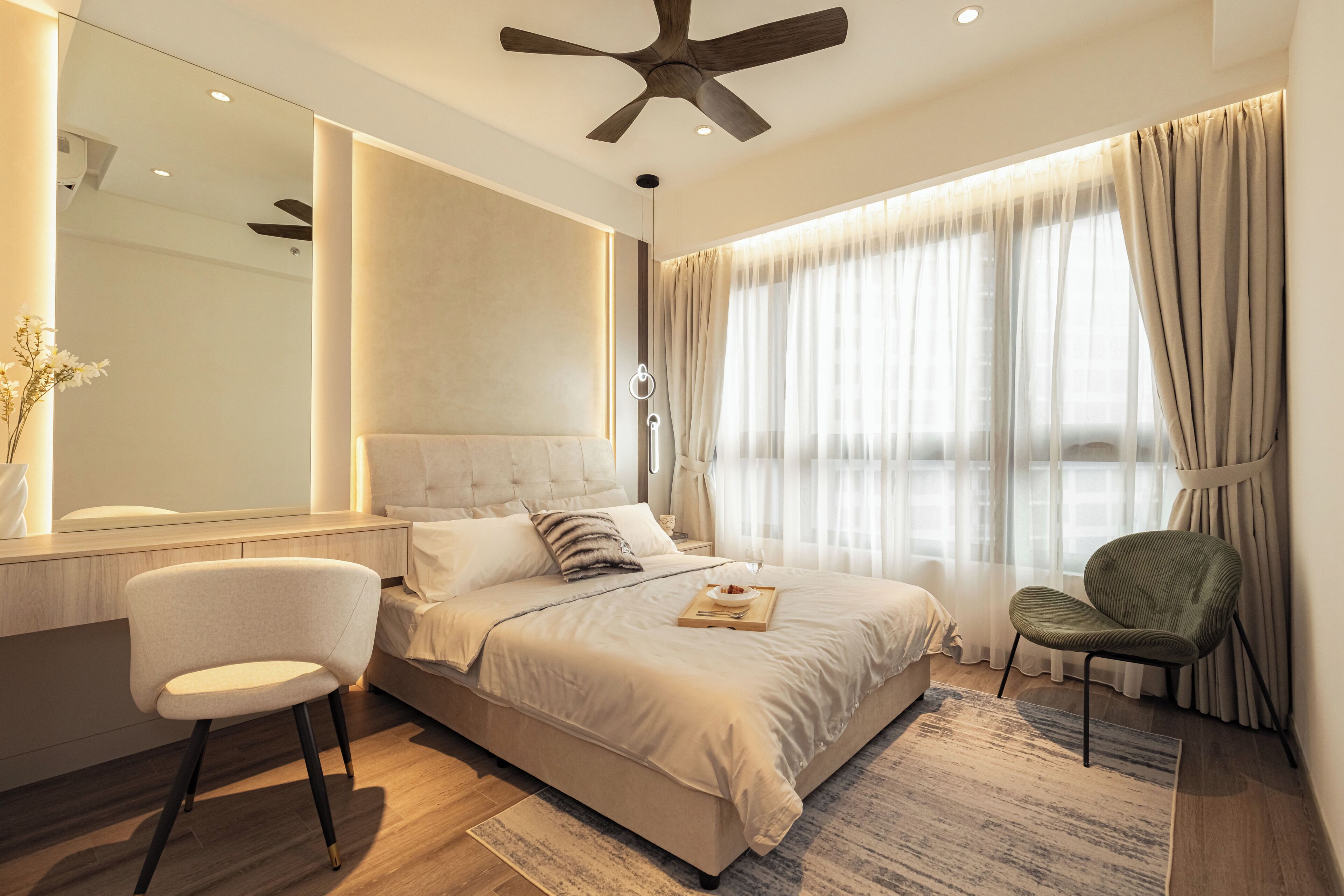 Une chambre moderne avec un grand lit, un ventilateur de plafond, une table de chevet, une chaise et un grand miroir.