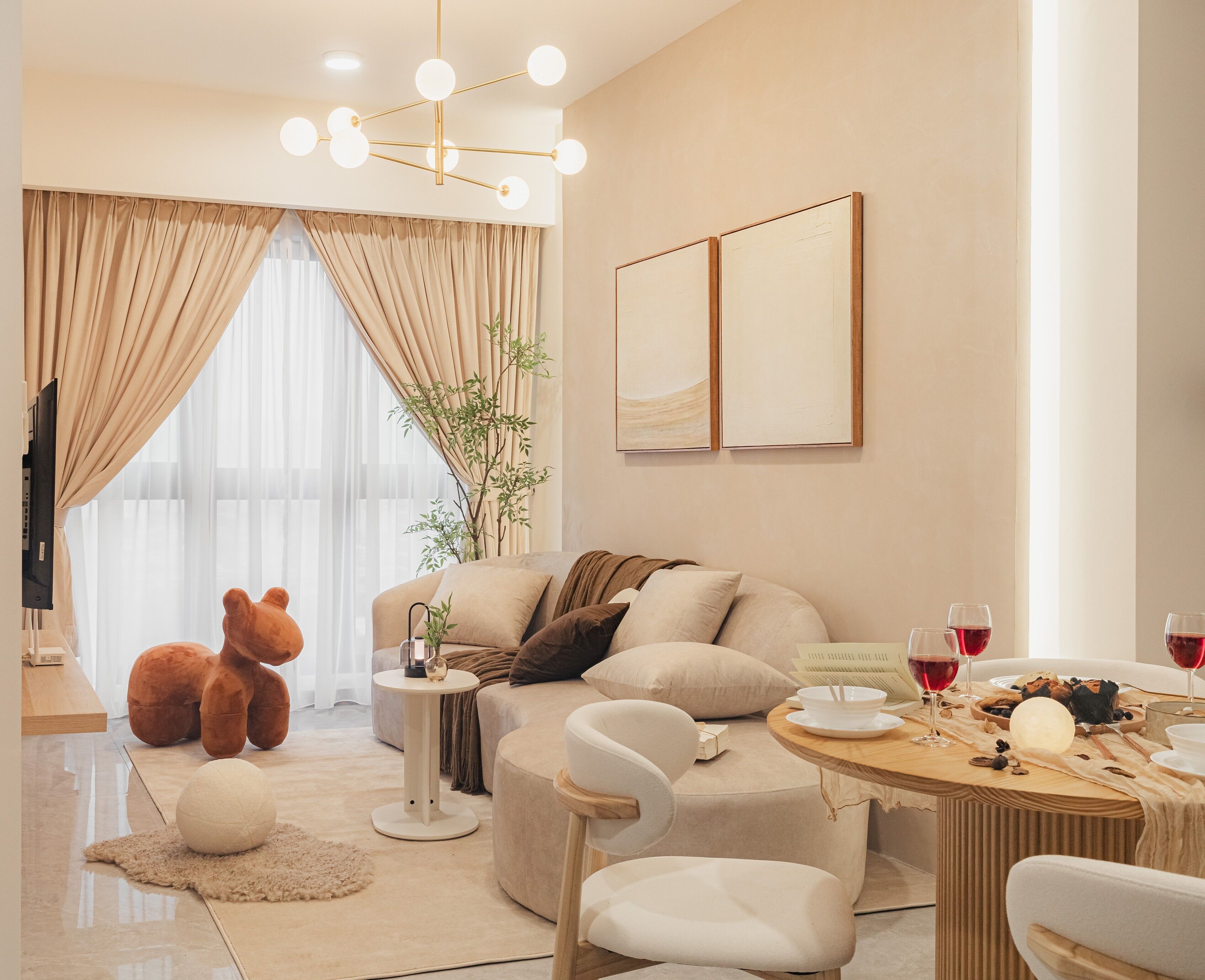 A modern living room with a sofa, chairs, a round table with wine glasses, and a teddy bear.