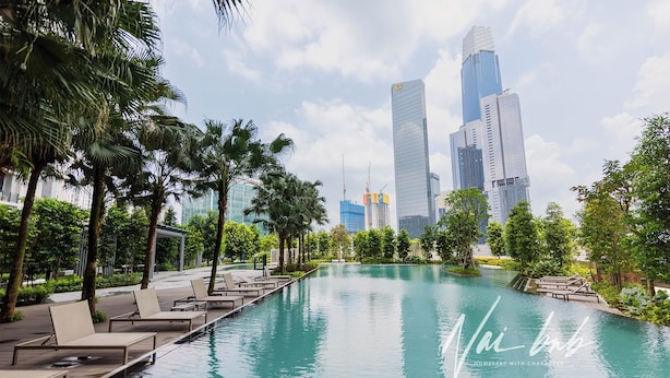 A swimming pool with lounge chairs and palm trees, surrounded by modern buildings. - NaiBnB @ Agile Bukit Bintang (Kuala Lumpur)